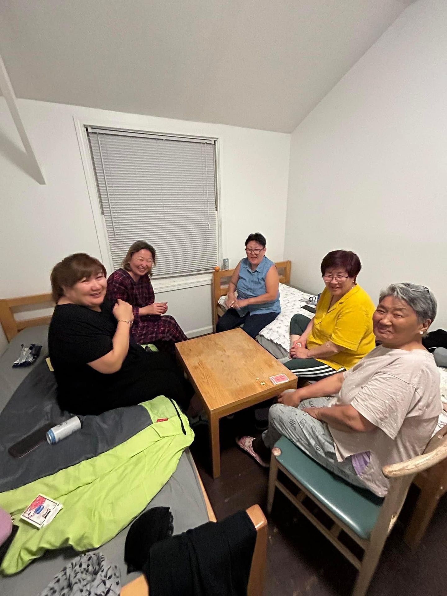 Group of people sitting around a wooden table in a small room, smiling and interacting.